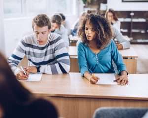 A student glancing at someone else’s test during an exam, symbolising the habit of focusing on others instead of staying grounded in your own life.